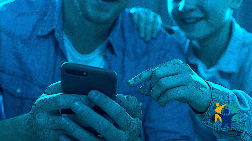 Father and son using a smartphone together as part of cyberbullying prevention efforts