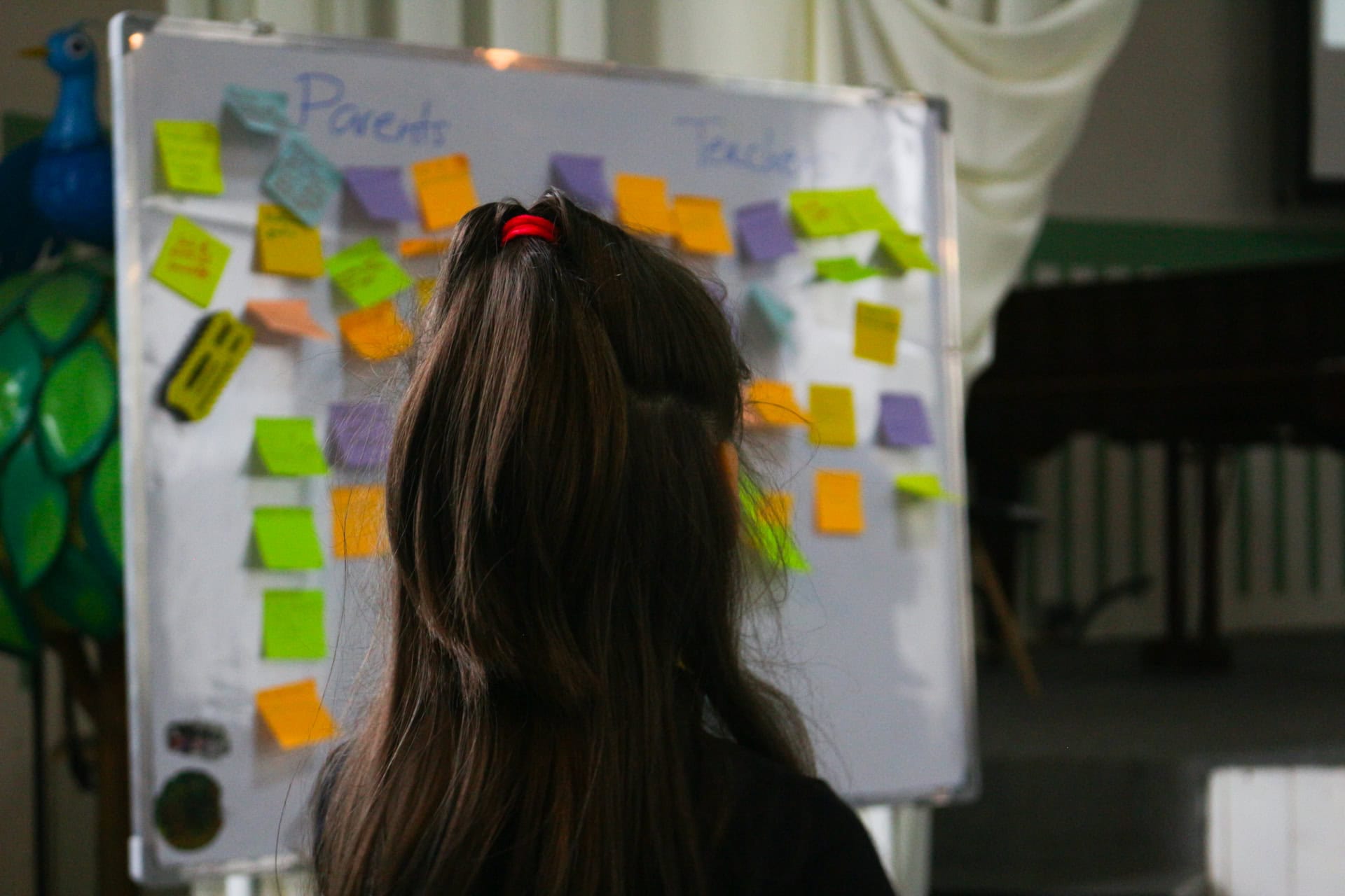 A child viewed from behind, looking at a board with elements of Teacher Training and Parental Training, highlighting Children, Parents, and Educators as core IPA training focus areas.