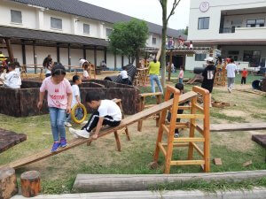 An Anji playground featuring open-ended materials like planks, barrels, and ladders, designed for true play experiences